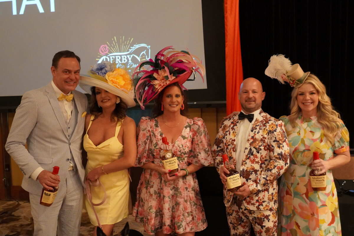 Five adults dressed in fancy Kentucky Derby outfits with awards